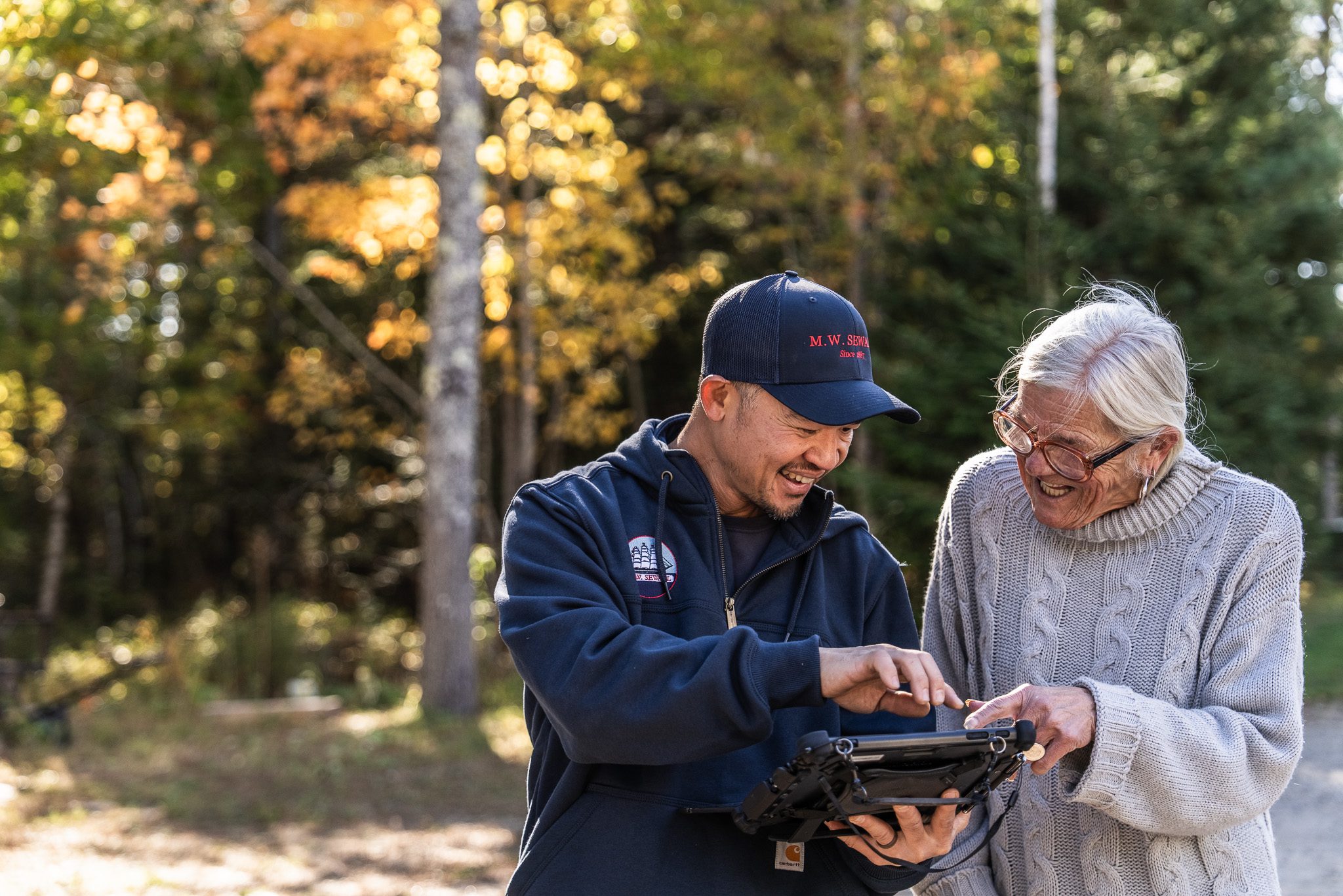 Professional heating experts dedicated to keeping your Maine home warm. M.W. Sewall service technician discussing high-efficiency heating maintenance with a customer in West Bath, Maine.