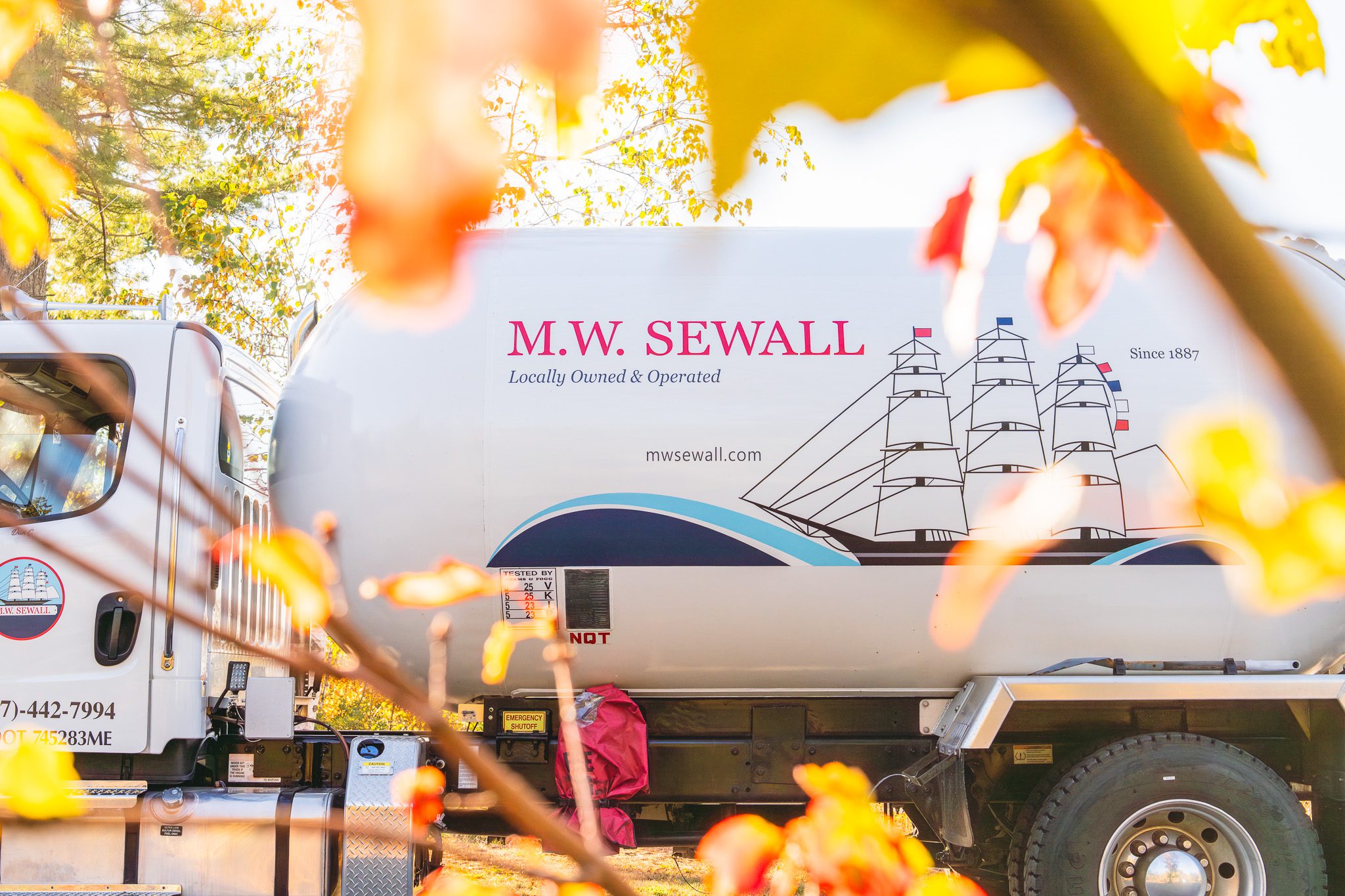 M.W. Sewall Side Of Propane Truck M.W. Sewall truck parked through the fall leaves.